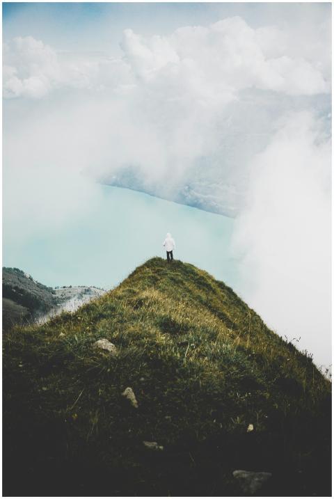 Person standing on a grassy cliff overlooking a mi