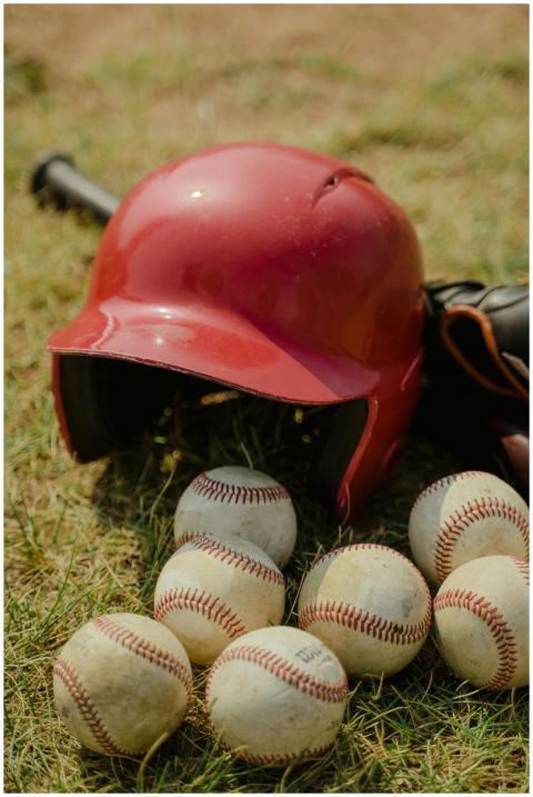 A red baseball helmet and multiple baseballs on a