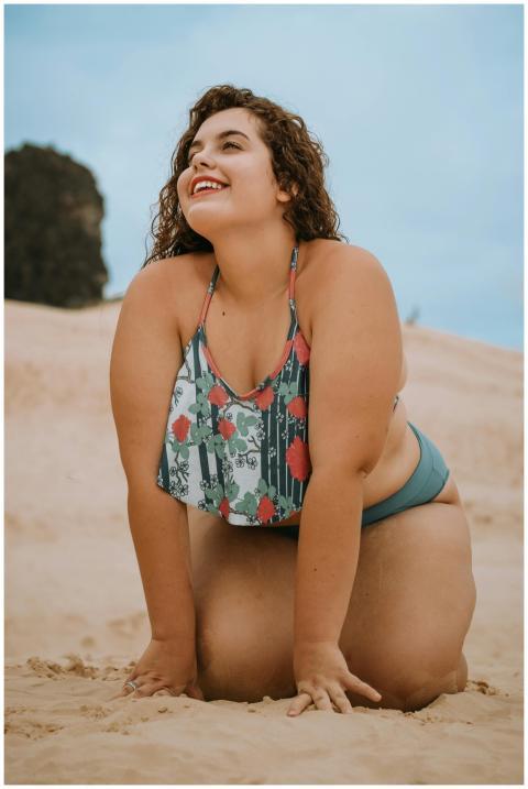 A cheerful woman poses confidently on a sandy beac