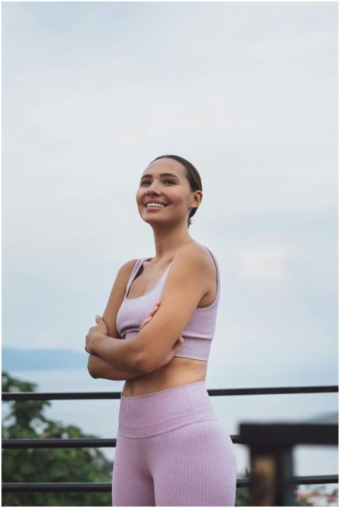 Smiling woman with arms crossed, wearing a sports