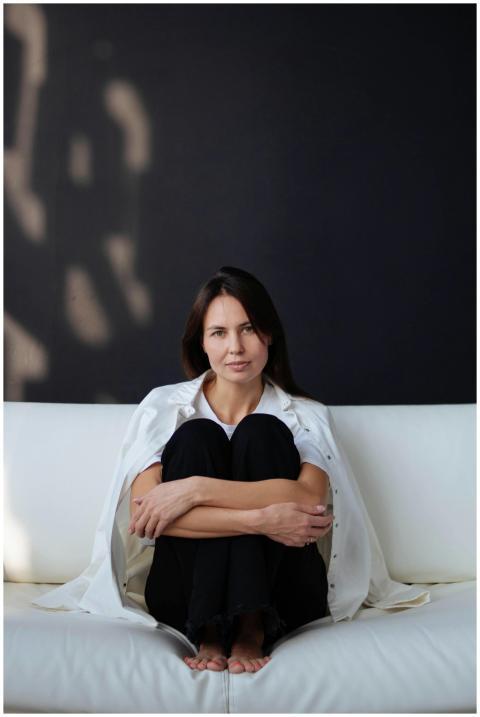 A relaxed portrait of a woman in casual attire sit
