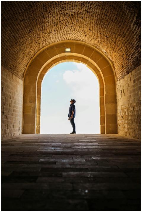 Man silhouetted in ancient stone archway exploring