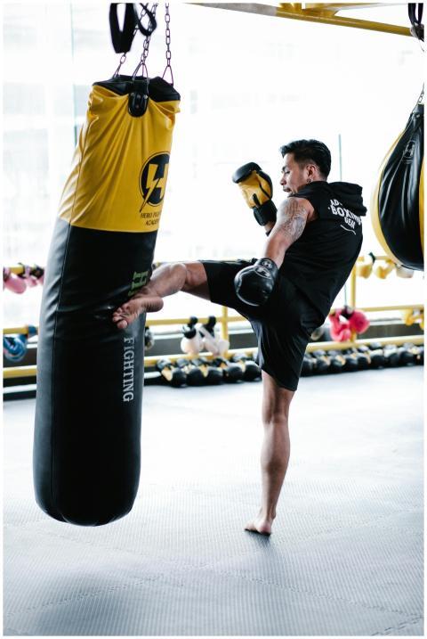 A fit tattooed man training with a yellow punching