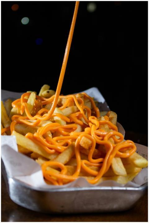 Close-up of French fries with rich cheese sauce, p