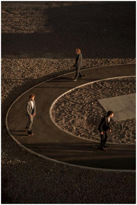 Three men skateboarding on a circular path in suit