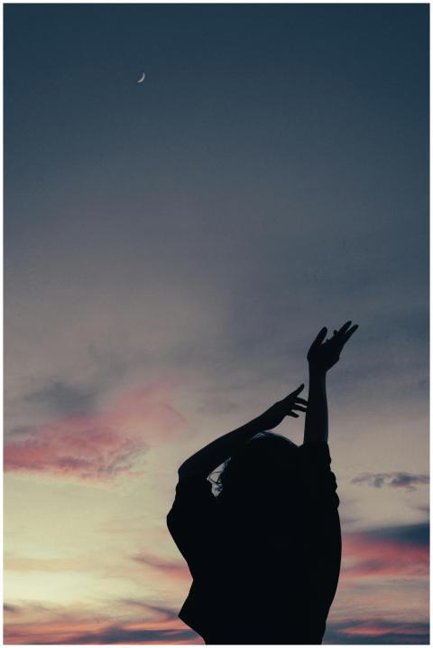 Silhouette of a woman with raised arms against a c