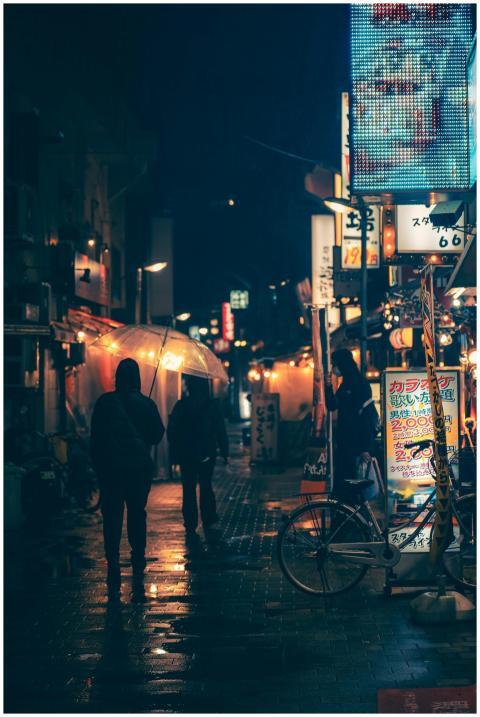 A vibrant, rainy urban street at night with pedest