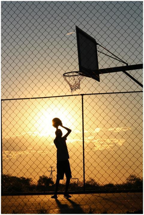 Silhouetted athlete playing basketball on an outdo