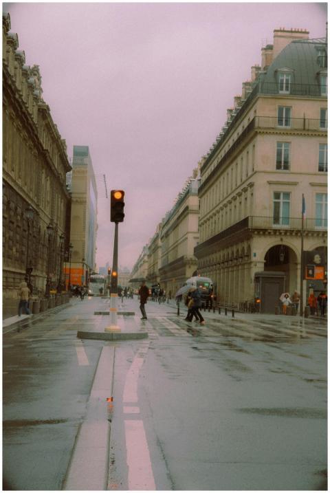 People walking through a rainy street in Paris wit