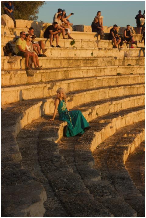 People relax in an ancient stone amphitheater duri