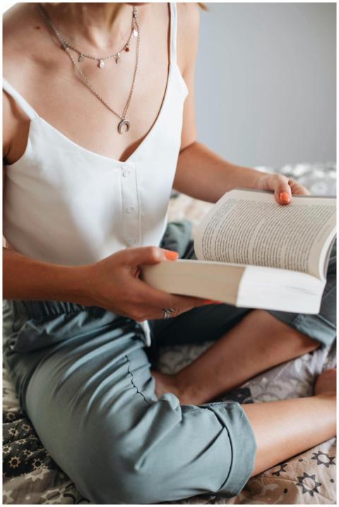 Woman sitting cross-legged, reading an open book i