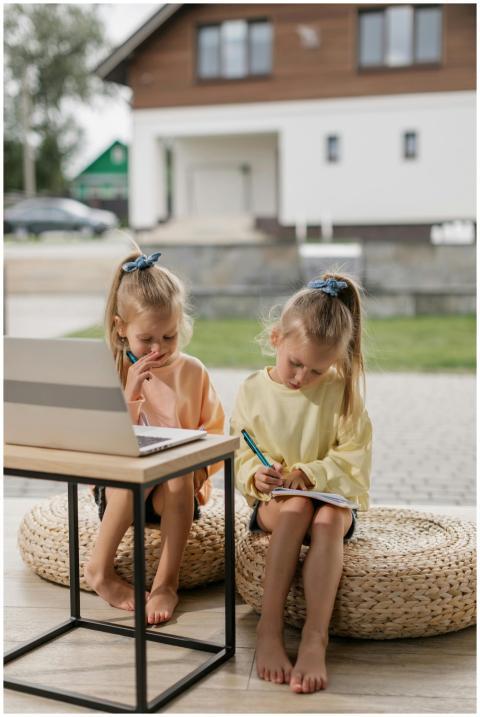 Two young girls learning online together, writing