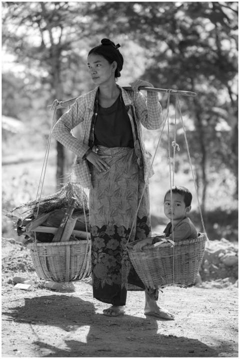 A mother carries her child in a basket on a sunny