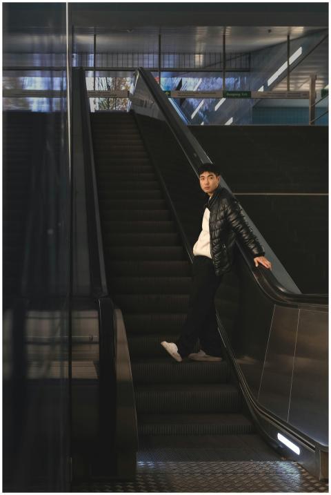 Young man in winter jacket standing on an escalato