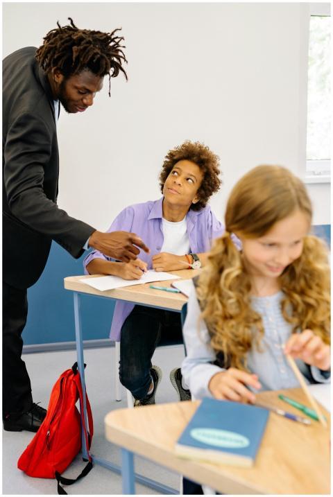 A teacher assists a diverse group of students in a