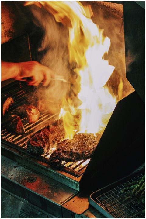Close-up of steak grilling over high flames, a cla