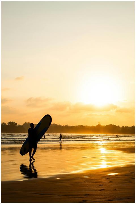 Silhouette of a surfer walking along Weligama Beac