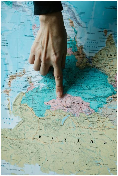 A hand points at Mongolia on a geographical map, s