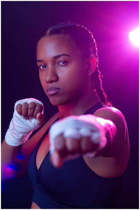 Strong female boxer in sports bra with hand wraps,