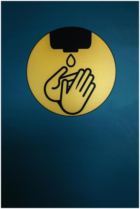Symbolic image of hand sanitizing sign on a blue b