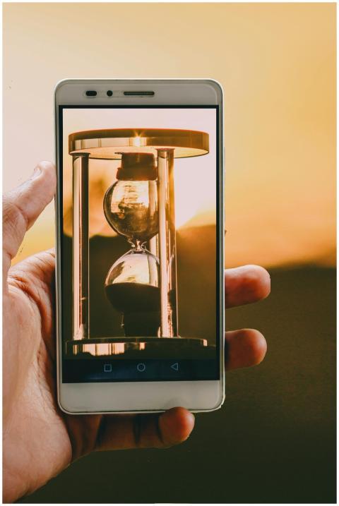 Hand holding smartphone with hourglass image at su