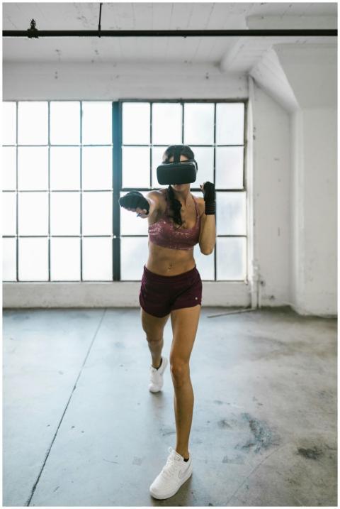 Woman in gym using virtual reality for workout wit