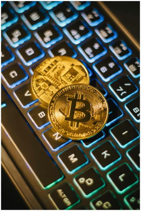Two Bitcoin coins resting on an illuminated keyboa