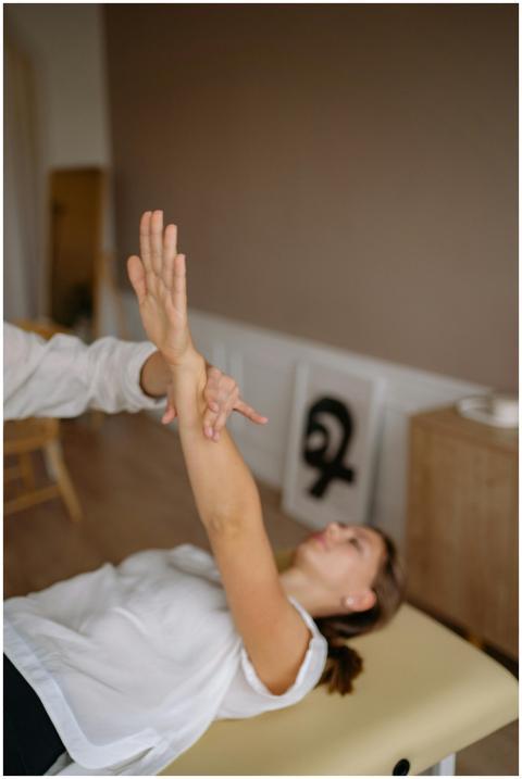 A therapist assists a woman in arm stretching ther