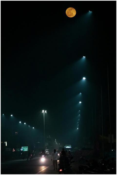 Unrecognizable people walking along illuminated st