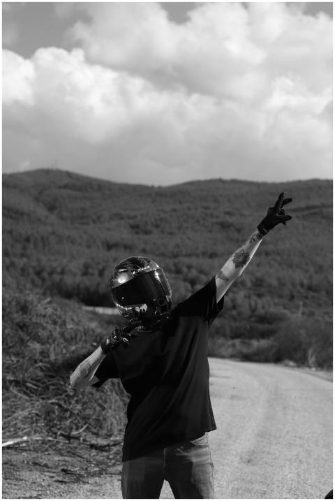 Motorcyclist posing with helmet on a rural road, s