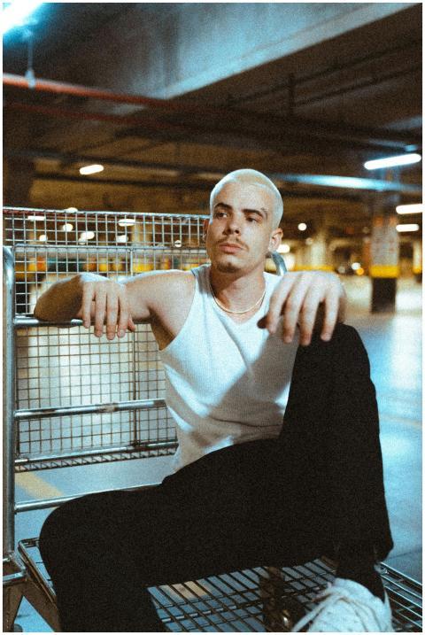 Man with dyed hair sitting in shopping cart in a g