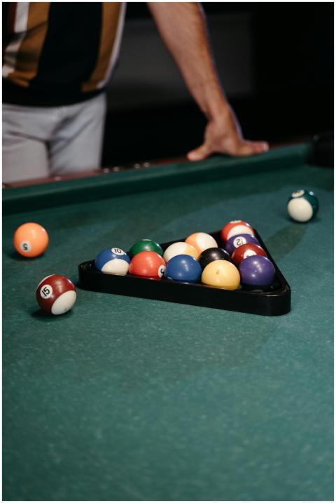 A close-up of a person setting up billiard balls o