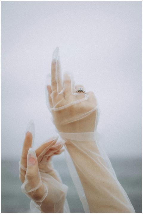 Delicate hands in sheer gloves reaching upwards un