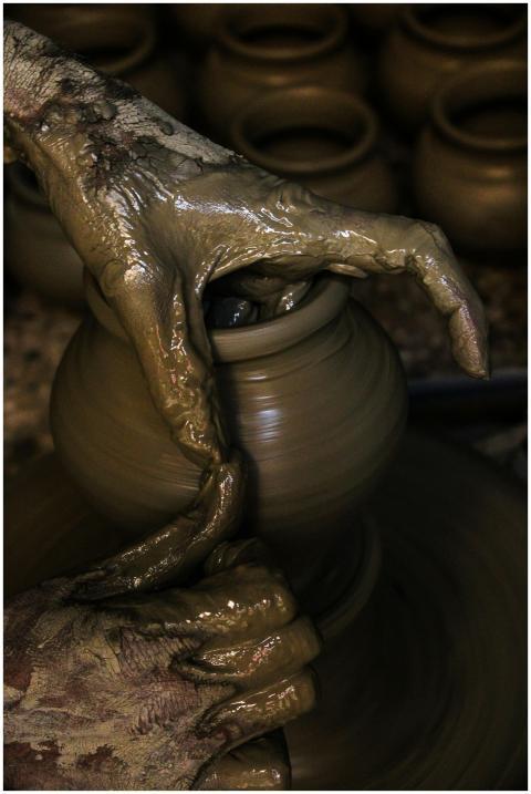 Close-up of hands shaping clay into pottery on a w
