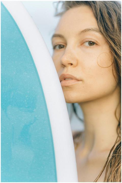 Close-up portrait of a woman beside a surfboard, h