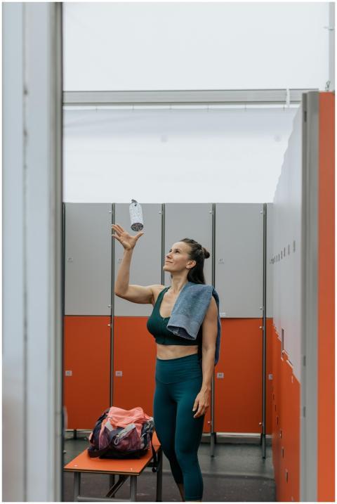 Woman in gym changing room with a towel and water