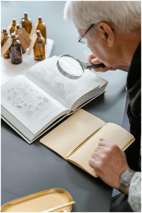 Elderly person reading botanical book with magnify