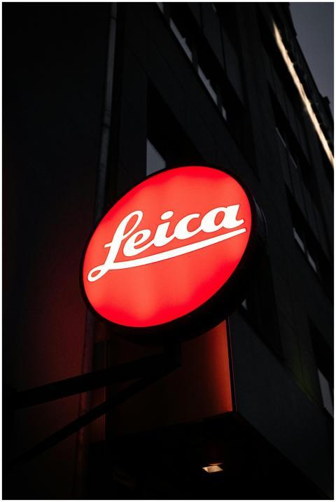 A bright red illuminated Leica store sign in an ur