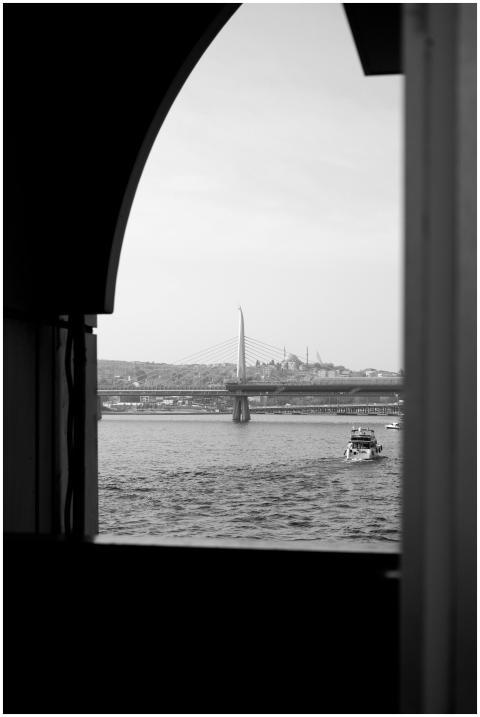 Black and white view of a bridge with a boat passi