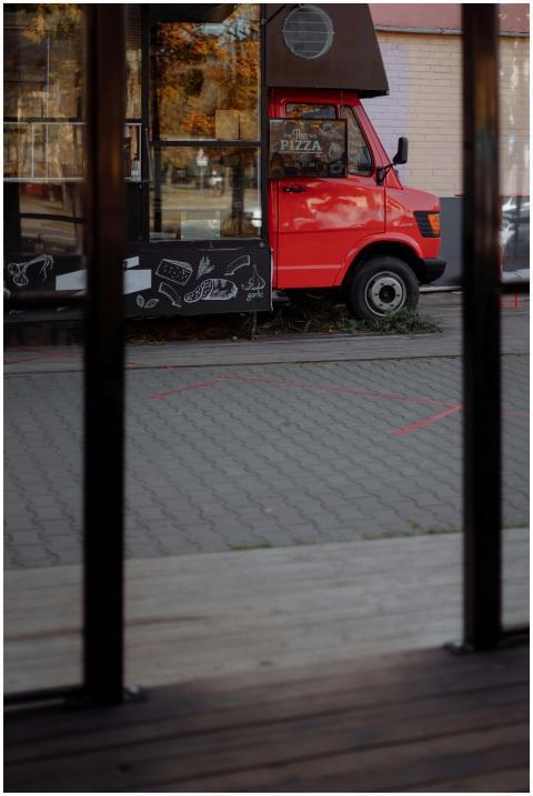 A vibrant red food truck with artistic chalkboard