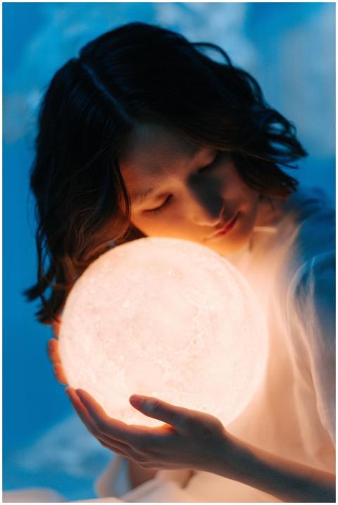 Asian woman embracing a glowing orb, evoking a dre
