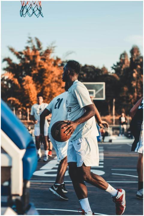Group of men playing basketball outdoors during su