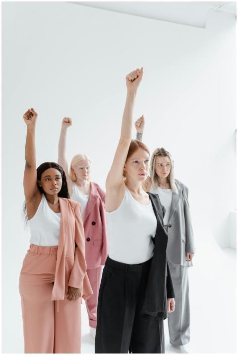 Four women of diverse ethnicities raising fists in