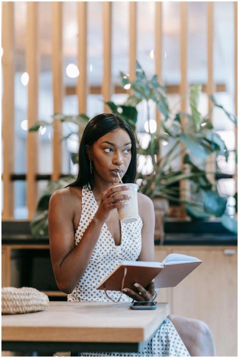 Chic woman in polka dot dress enjoying a drink whi