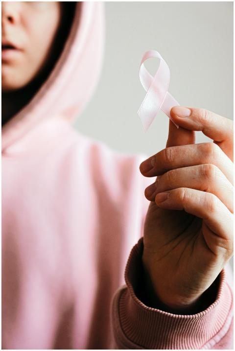 Close-up of a person holding a pink ribbon symboli