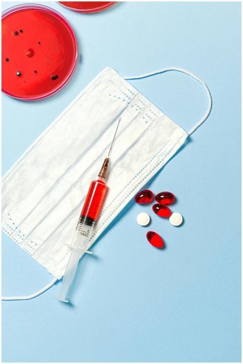 Face mask, syringe, and pills on a blue background