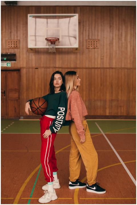 Two women in casual outfits pose together on an in