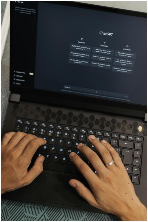 Hands typing on a laptop displaying the ChatGPT in