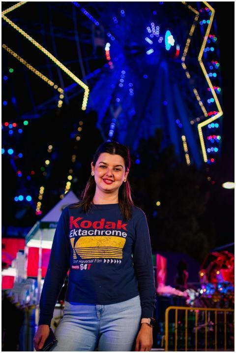 A woman in a Kodak shirt smiles at a night carniva