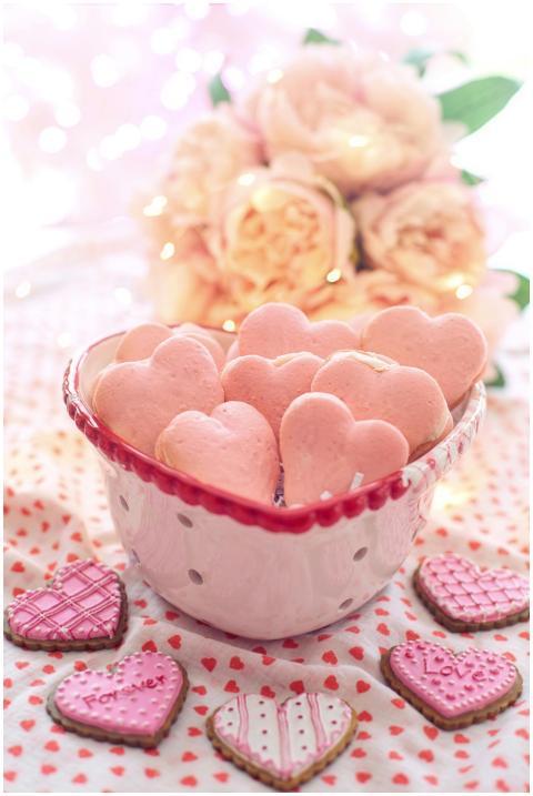 Heart-shaped pink macarons in a bowl with roses, p